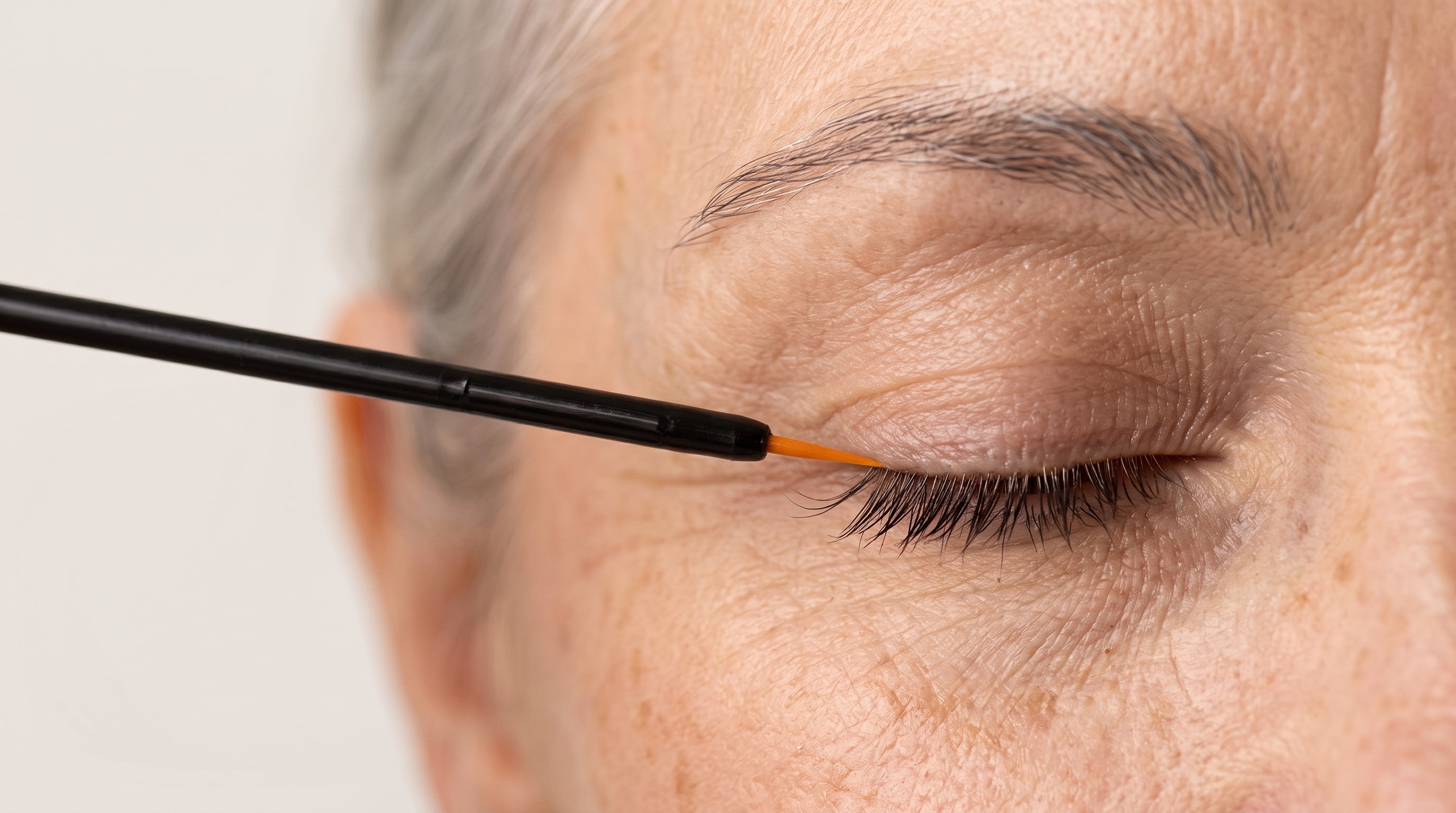 Woman in her 50s applying eyelash growth serum